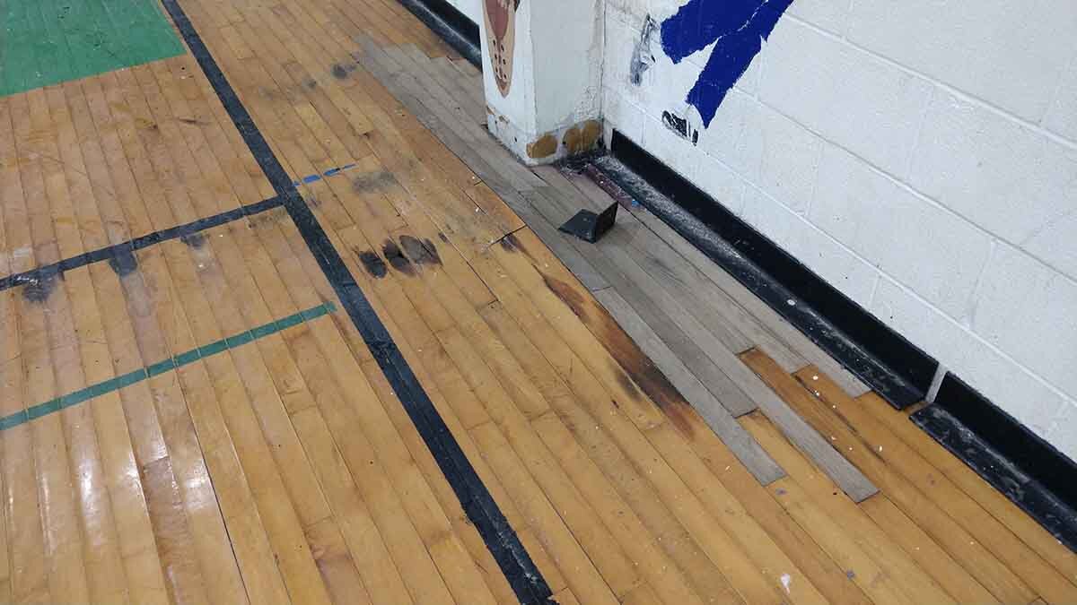 moisture damage, rot, and patchwork on hardwood gym floor at First Mexican Baptist Church